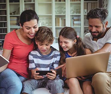 Happy Family Using Devices on the Couch