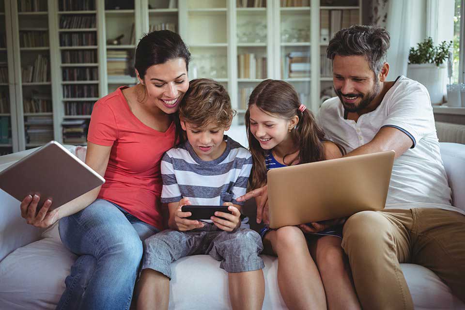 Happy Family Using Devices on the Couch